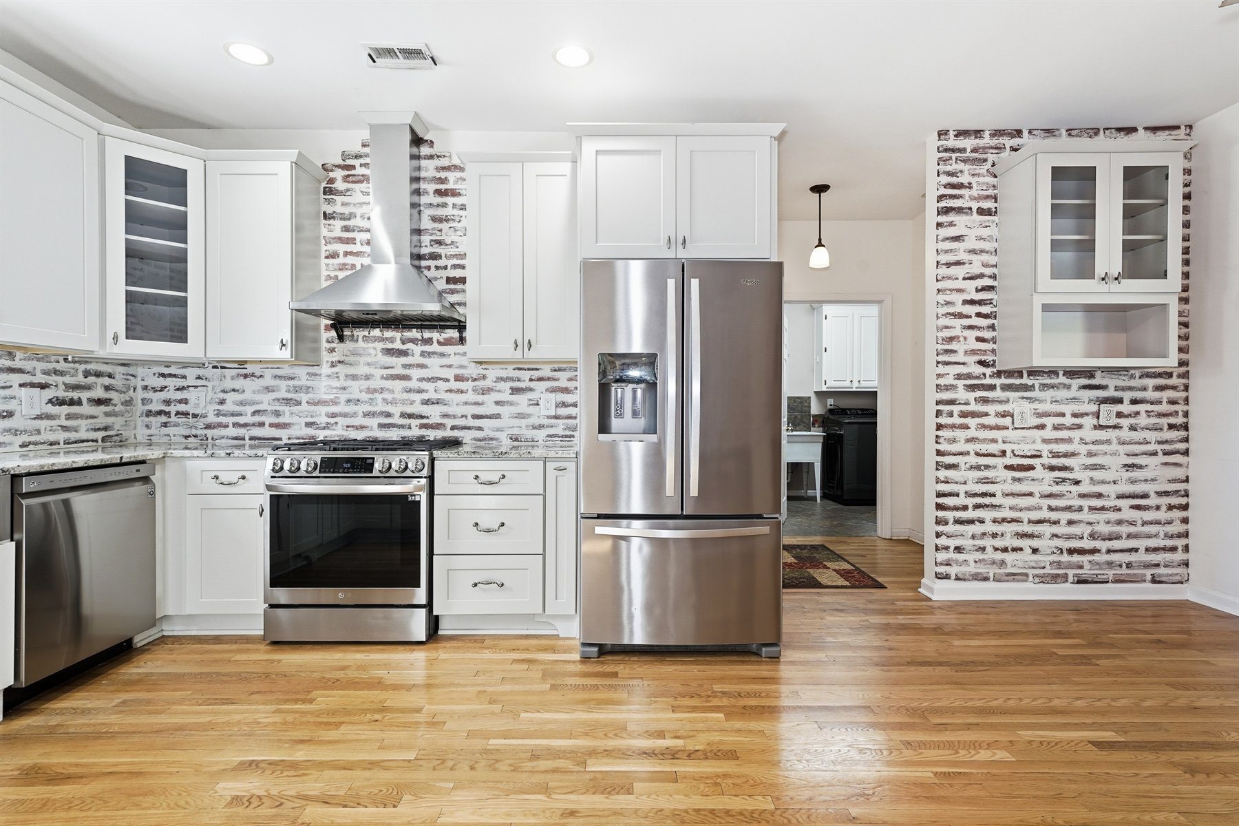 Kitchen with white cabinetry and exposed brick wall