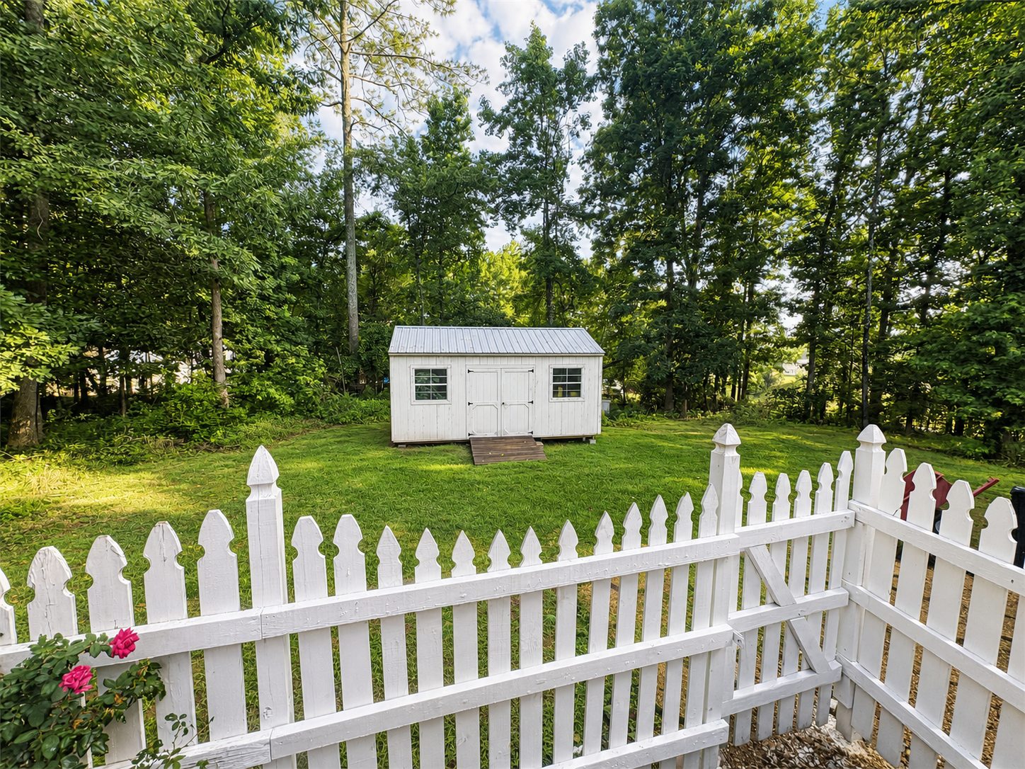 Shed in the backyard beyond the white picket fence